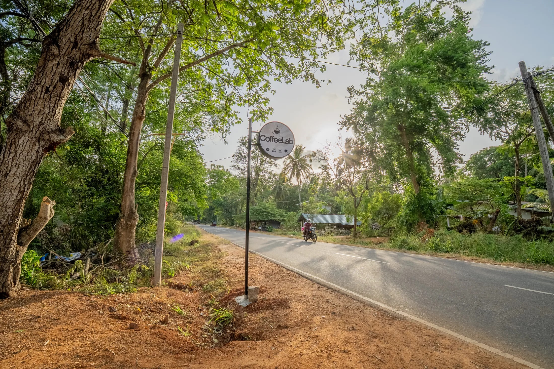 CoffeeLab roadside sign surrounded by tropical greenery in Sigiriya